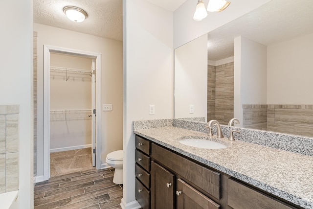 bathroom with vanity, a textured ceiling, and toilet