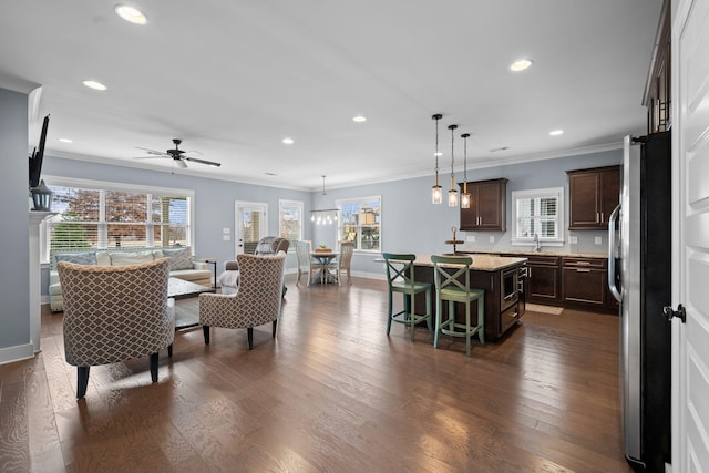 interior space featuring stainless steel refrigerator, a center island, hanging light fixtures, and dark wood-type flooring