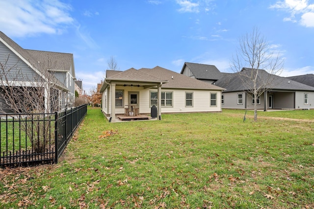 back of property featuring ceiling fan and a yard