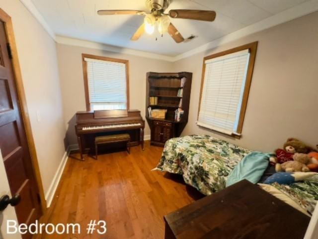 bedroom with hardwood / wood-style flooring, ceiling fan, and ornamental molding