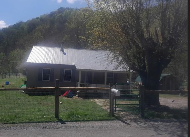 view of front of home with metal roof, a gate, a front lawn, and a fenced front yard