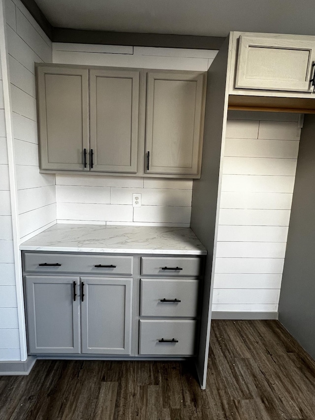 bar featuring gray cabinets, light stone counters, and dark hardwood / wood-style floors