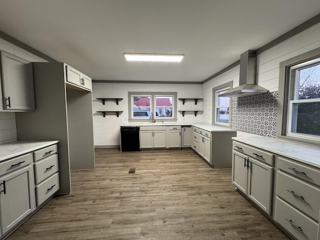 kitchen with gray cabinets, hardwood / wood-style flooring, wall chimney range hood, and black dishwasher