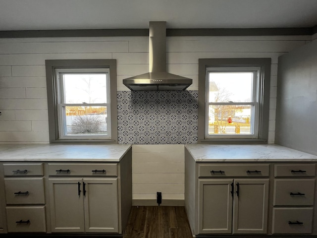 kitchen featuring dark hardwood / wood-style flooring, a wealth of natural light, and wall chimney range hood