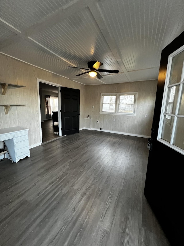 unfurnished living room with wood walls, dark hardwood / wood-style flooring, and ceiling fan