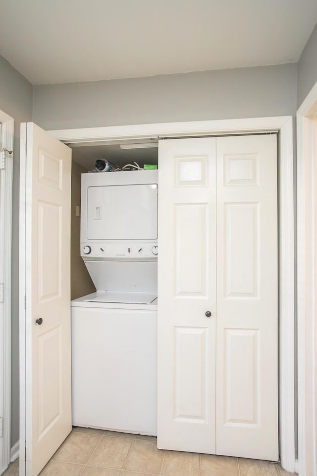 laundry room featuring stacked washer / dryer and light tile patterned floors