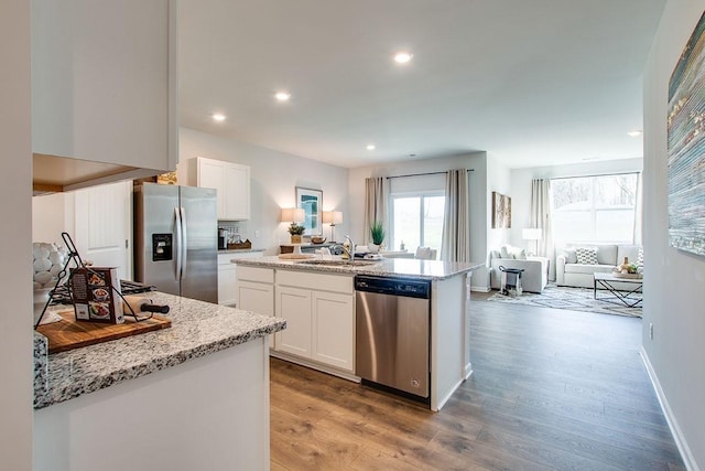 kitchen featuring white cabinets, hardwood / wood-style flooring, a center island with sink, and appliances with stainless steel finishes