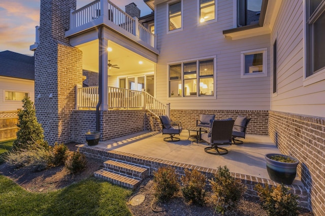 back house at dusk with a patio area and a balcony