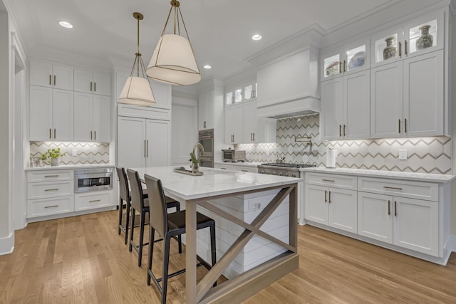 kitchen with white cabinets, light wood-type flooring, and premium range hood