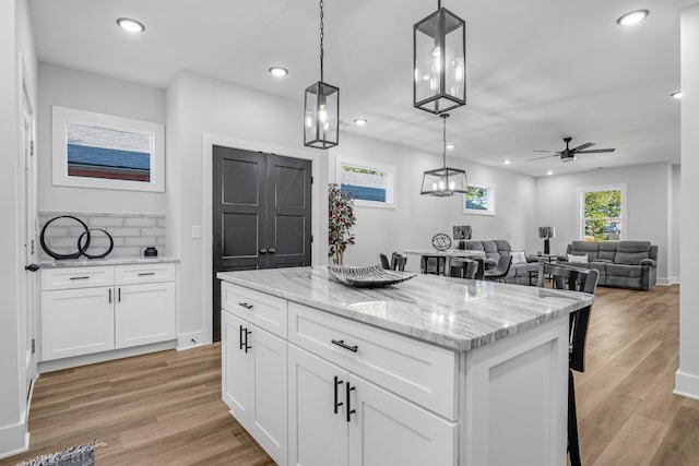 kitchen featuring white cabinets, pendant lighting, a kitchen island, and ceiling fan