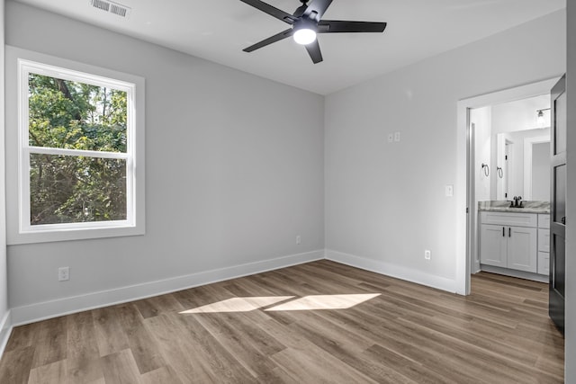 unfurnished bedroom with ensuite bath, light hardwood / wood-style flooring, and ceiling fan