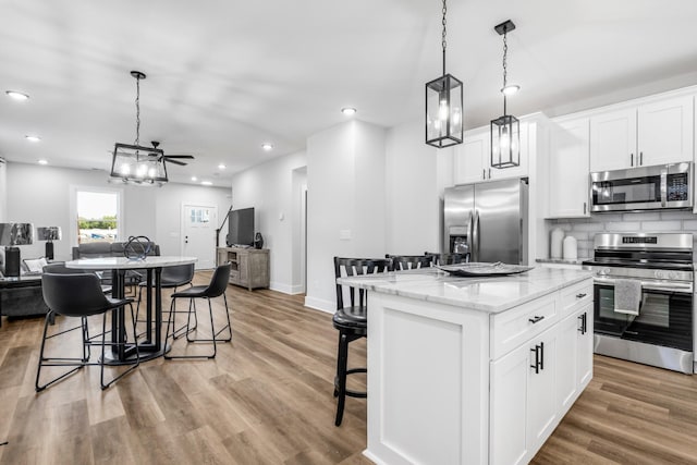 kitchen with a kitchen bar, appliances with stainless steel finishes, white cabinets, and a kitchen island