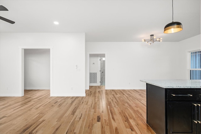 interior space with pendant lighting, light stone counters, ceiling fan, and light hardwood / wood-style flooring