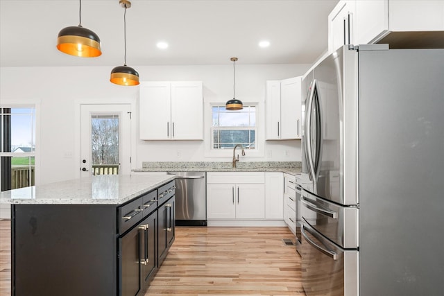 kitchen with pendant lighting, white cabinetry, stainless steel appliances, light stone countertops, and a kitchen island