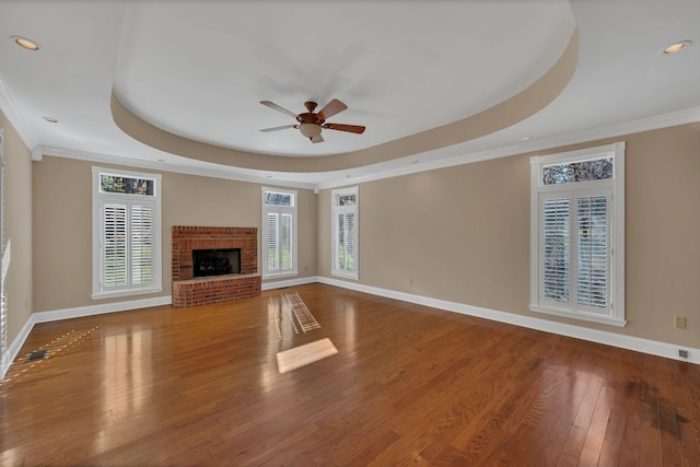 unfurnished living room with a tray ceiling, ceiling fan, hardwood / wood-style floors, and ornamental molding