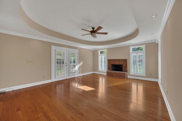 unfurnished living room featuring french doors, a raised ceiling, ceiling fan, crown molding, and hardwood / wood-style flooring