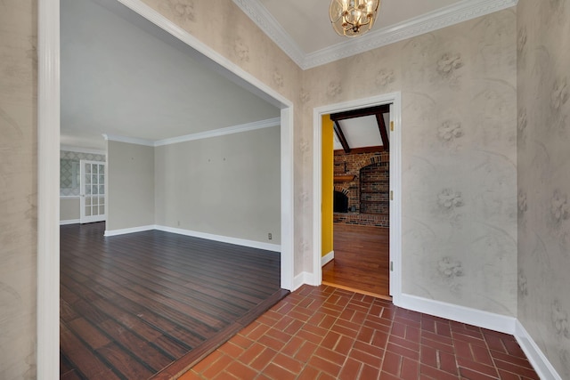 unfurnished room featuring a notable chandelier, dark hardwood / wood-style flooring, ornamental molding, and a brick fireplace