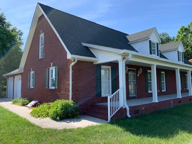exterior space with covered porch, a garage, and a yard
