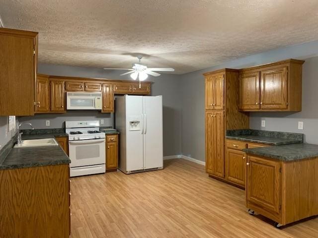kitchen with a textured ceiling, white appliances, sink, and light hardwood / wood-style flooring