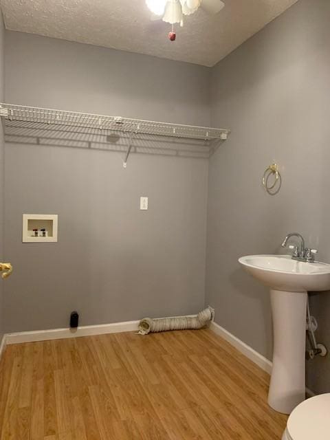 laundry room with washer hookup, light hardwood / wood-style floors, and a textured ceiling