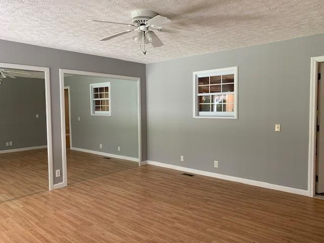 unfurnished room featuring hardwood / wood-style flooring, ceiling fan, and a textured ceiling