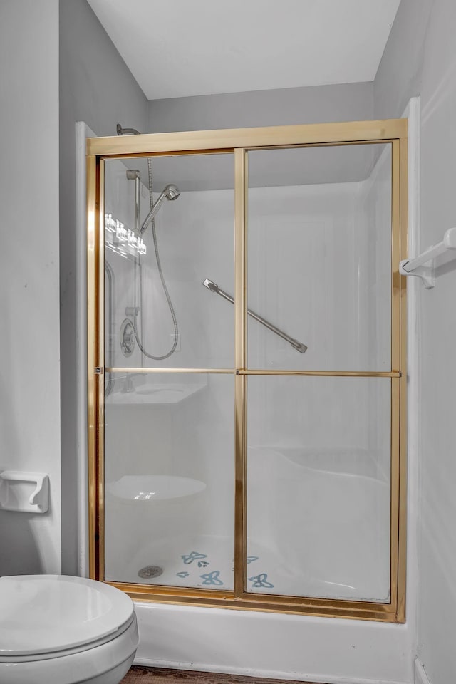 bathroom featuring toilet and a shower with shower door