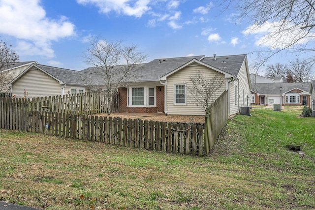 rear view of property featuring a lawn and cooling unit