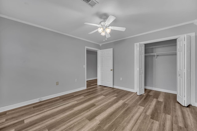 unfurnished bedroom with wood-type flooring, a closet, ceiling fan, and crown molding