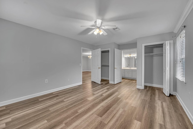 unfurnished bedroom with ceiling fan, light wood-type flooring, ornamental molding, and ensuite bath