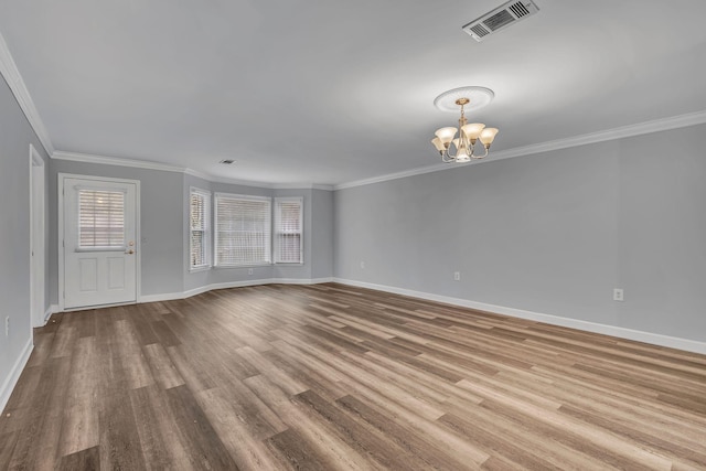 unfurnished living room featuring hardwood / wood-style floors, ornamental molding, and an inviting chandelier