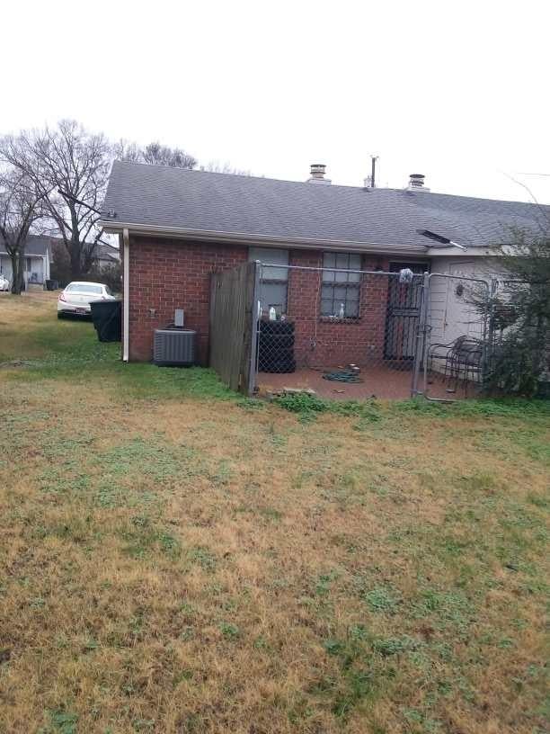 rear view of house featuring a yard and central air condition unit