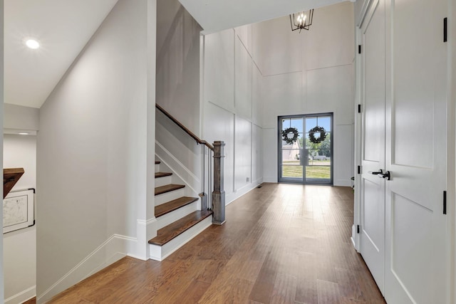 entryway featuring hardwood / wood-style flooring, a high ceiling, and a chandelier