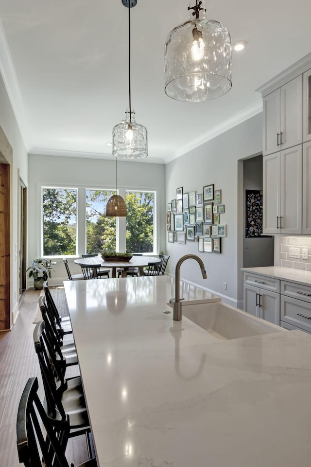 kitchen featuring backsplash, crown molding, sink, and hanging light fixtures