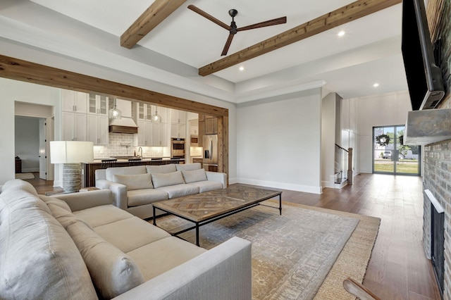 living room with dark hardwood / wood-style flooring, ceiling fan, sink, beam ceiling, and a high ceiling