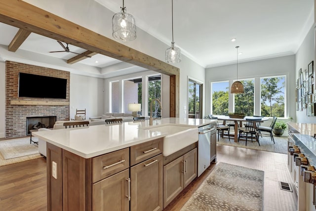 kitchen with a center island with sink, decorative light fixtures, stainless steel dishwasher, and a fireplace