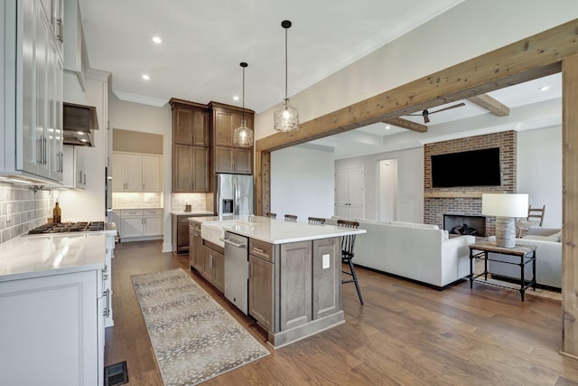 kitchen featuring decorative backsplash, a spacious island, sink, hanging light fixtures, and a breakfast bar area