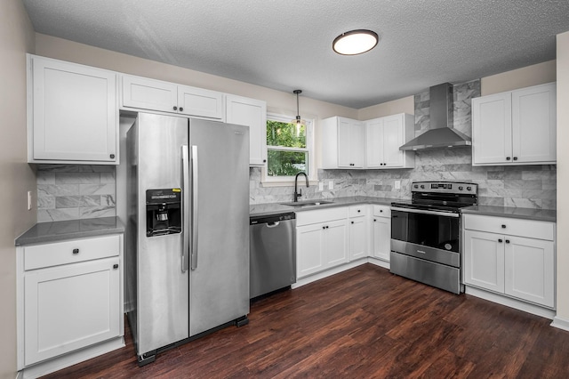 kitchen with white cabinetry, sink, wall chimney range hood, dark hardwood / wood-style floors, and appliances with stainless steel finishes