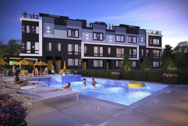 pool at dusk with a patio area