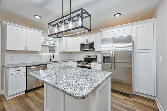 kitchen with sink, white cabinets, stainless steel appliances, and hardwood / wood-style flooring