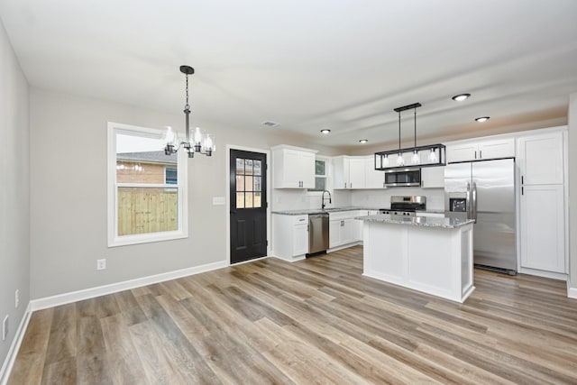 kitchen with hanging light fixtures, white cabinets, light hardwood / wood-style floors, and appliances with stainless steel finishes