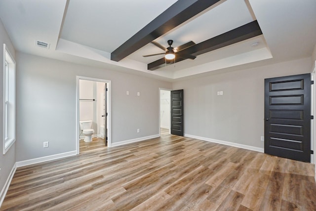 unfurnished bedroom featuring ensuite bathroom, a raised ceiling, ceiling fan, and light hardwood / wood-style floors