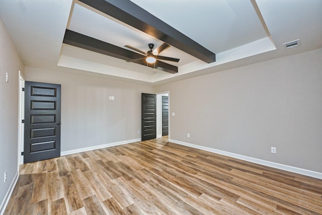 spare room featuring a tray ceiling, ceiling fan, beam ceiling, and hardwood / wood-style flooring