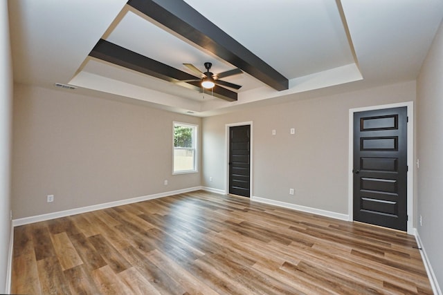 unfurnished room featuring wood-type flooring, a raised ceiling, ceiling fan, and beam ceiling