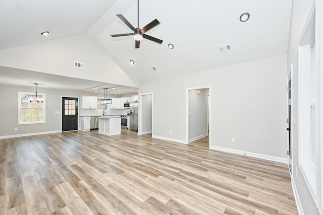 unfurnished living room with sink, high vaulted ceiling, light hardwood / wood-style floors, and ceiling fan with notable chandelier