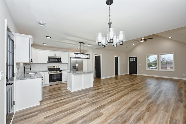 kitchen featuring a center island, lofted ceiling, light wood-type flooring, white cabinetry, and stainless steel appliances