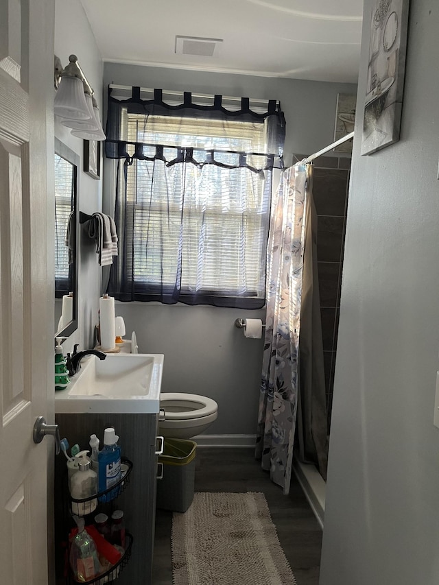 bathroom with hardwood / wood-style floors, vanity, toilet, and walk in shower