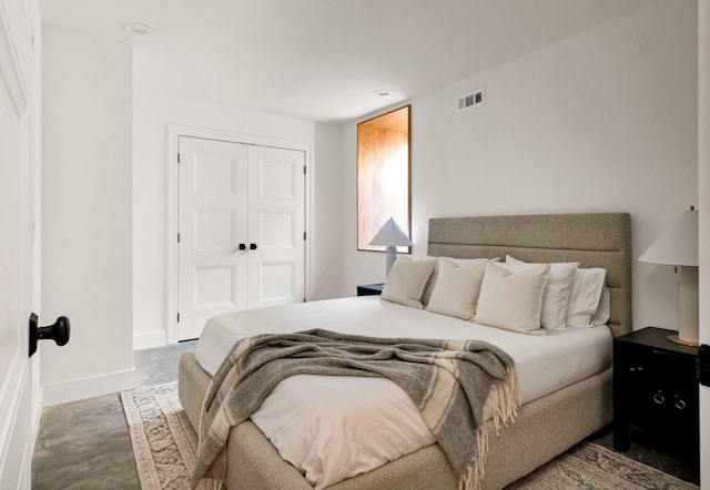 bedroom featuring baseboards, visible vents, concrete flooring, and a closet