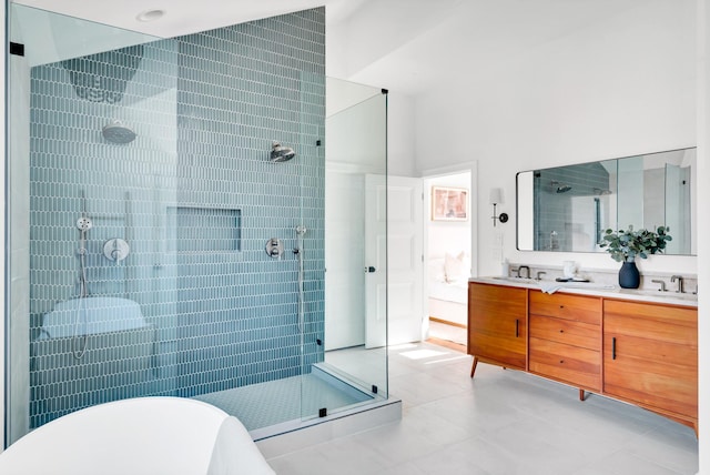 full bathroom featuring double vanity, a sink, a freestanding bath, and tiled shower