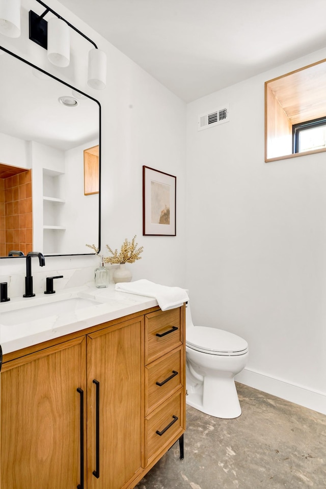 bathroom featuring toilet, concrete floors, vanity, and built in shelves