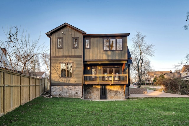 back of property featuring a yard, fence, and a wooden deck